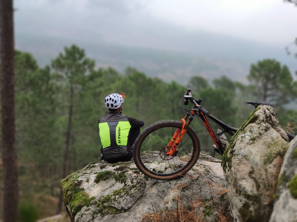 Personne assise avec son VTT regardant la montagne